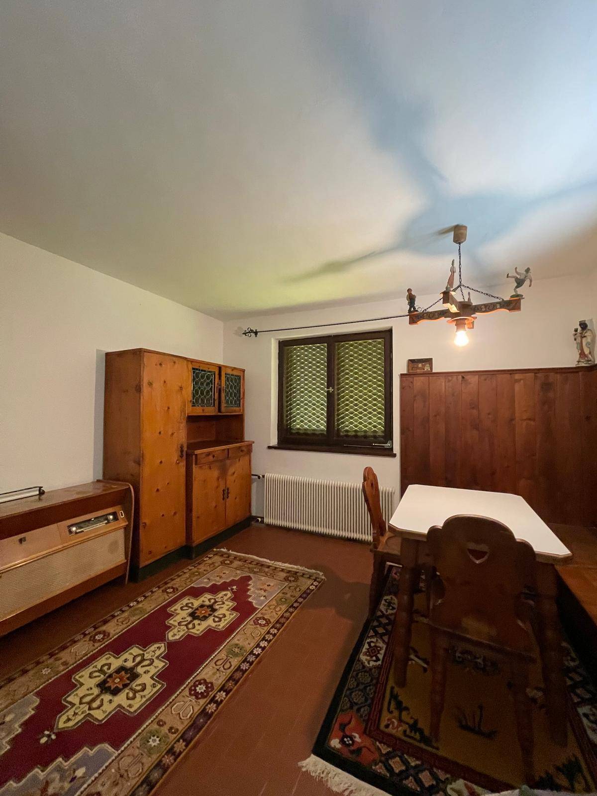 Gemütliches Esszimmer mit Holzvertäfelung, traditionellen Möbeln und Teppichboden.