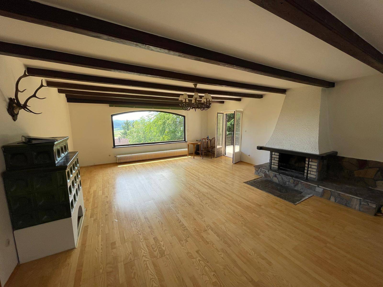Großzügiges Wohnzimmer mit Kachelofen, Kamin und weitem Blick in die Natur.