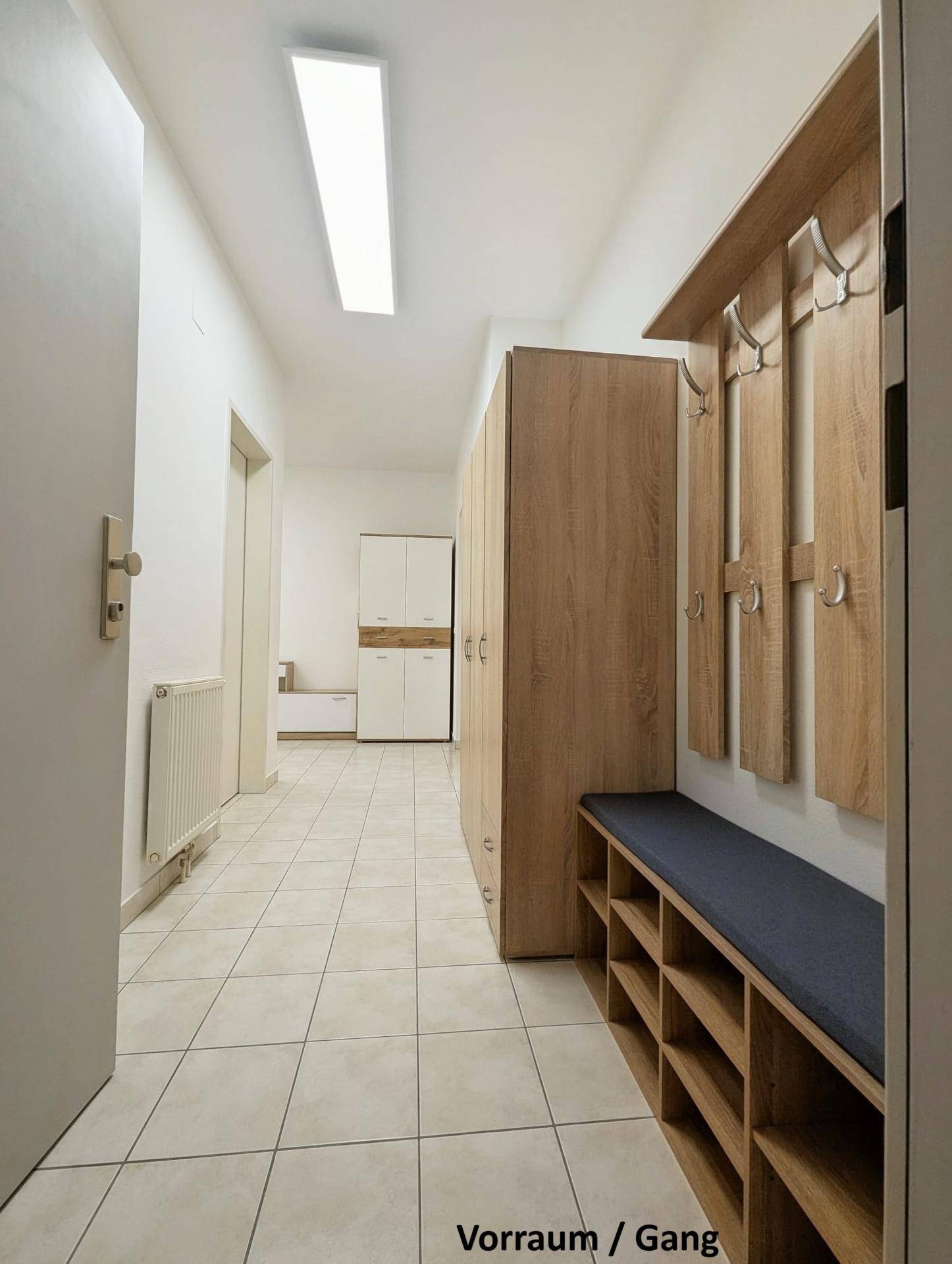 Langer Flur mit Fliesenboden, Garderobe und Schränken, der zu weiteren Räumen führt.