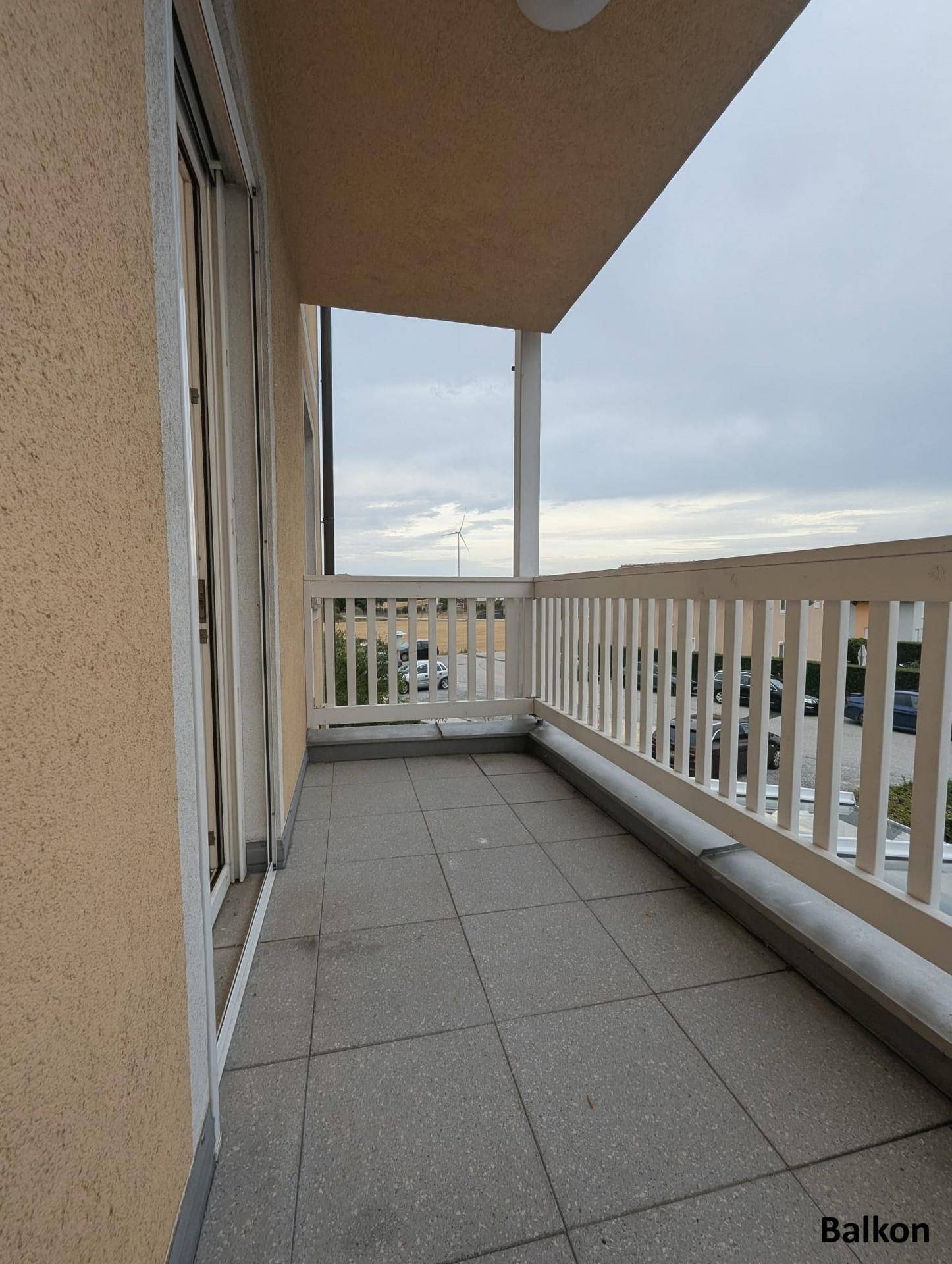 Geräumiger Balkon mit Fliesenboden und weißem Geländer, bietet einen weiten Ausblick.