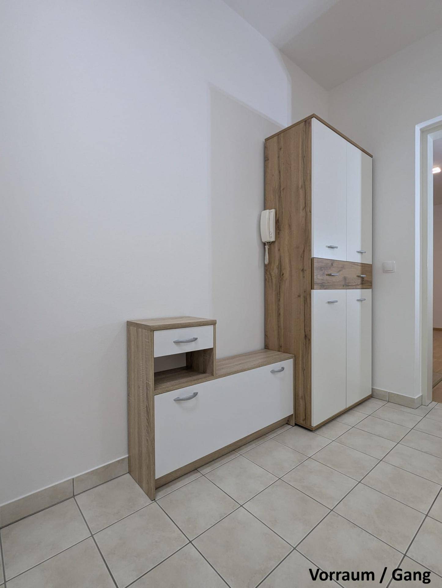 Moderner Flur mit Fliesenboden und praktischen Möbeln in Holz-Weiß-Kombination.