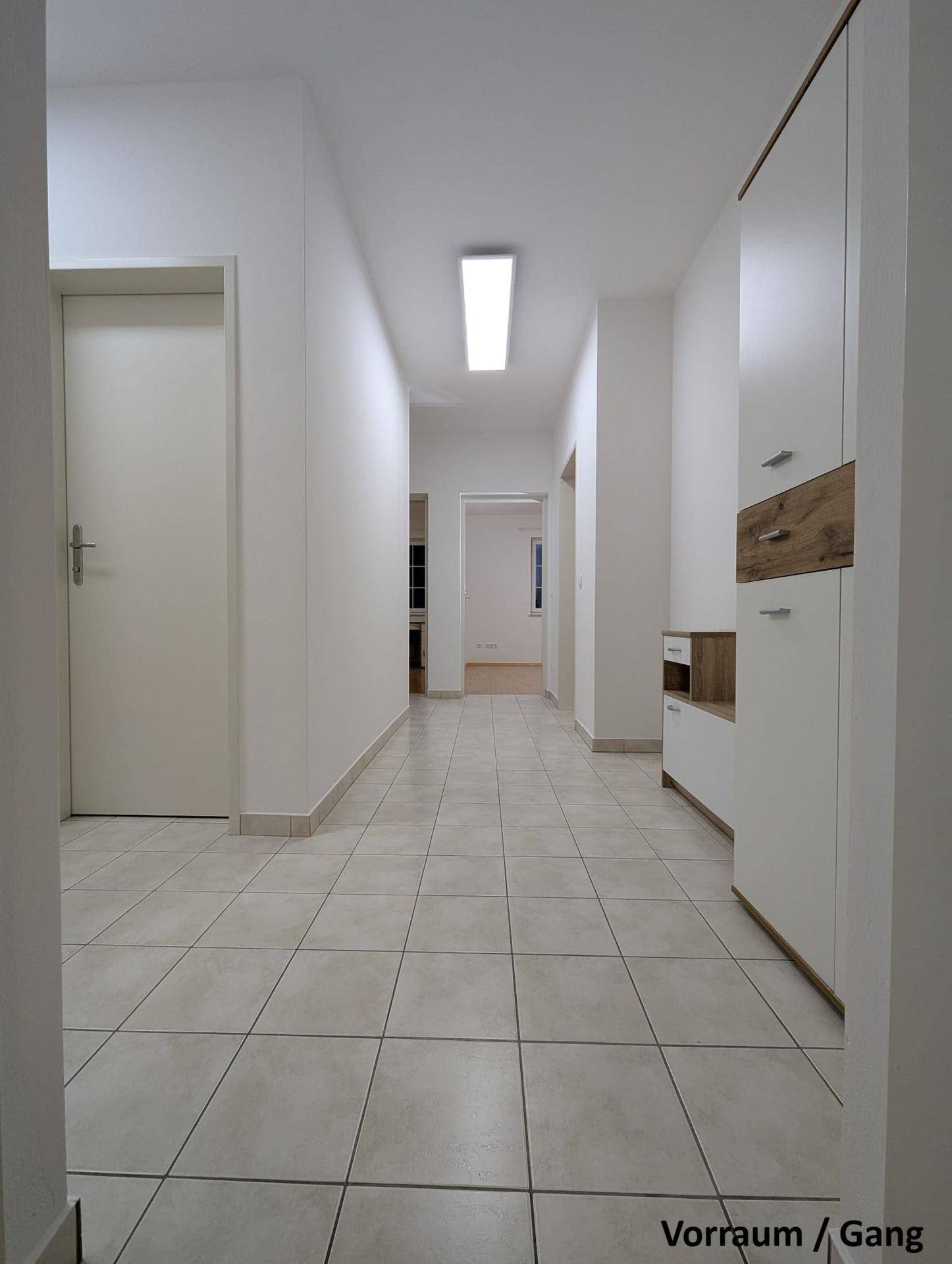Heller Flur mit Fliesenboden und Blick in den hinteren Bereich der Wohnung.
