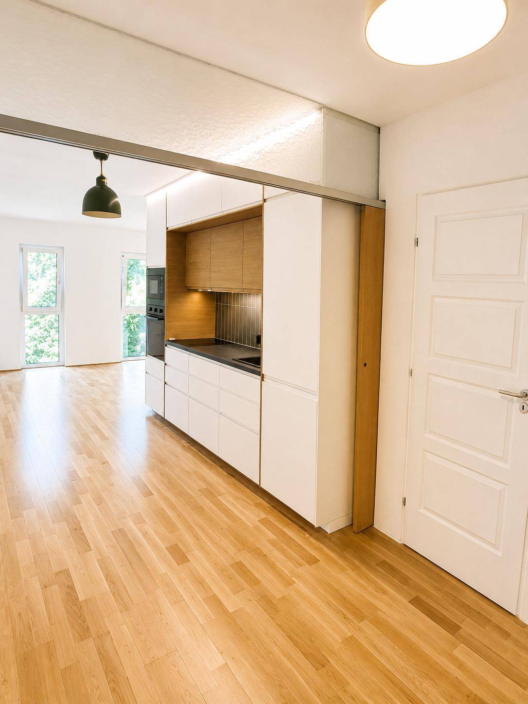 Moderne Einbauküche mit Holzdetails und hellem Parkettboden im offenen Wohnbereich.