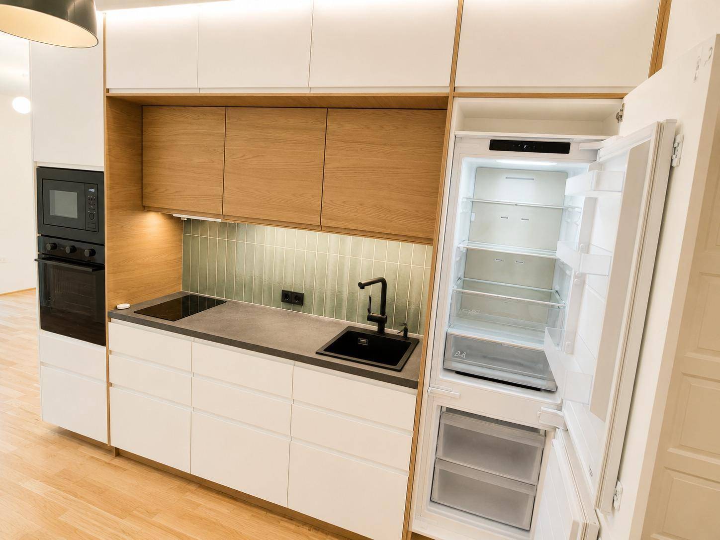 Integrierter Kühlschrank in der modernen Einbauküche mit Holz- und Weißfronten.
