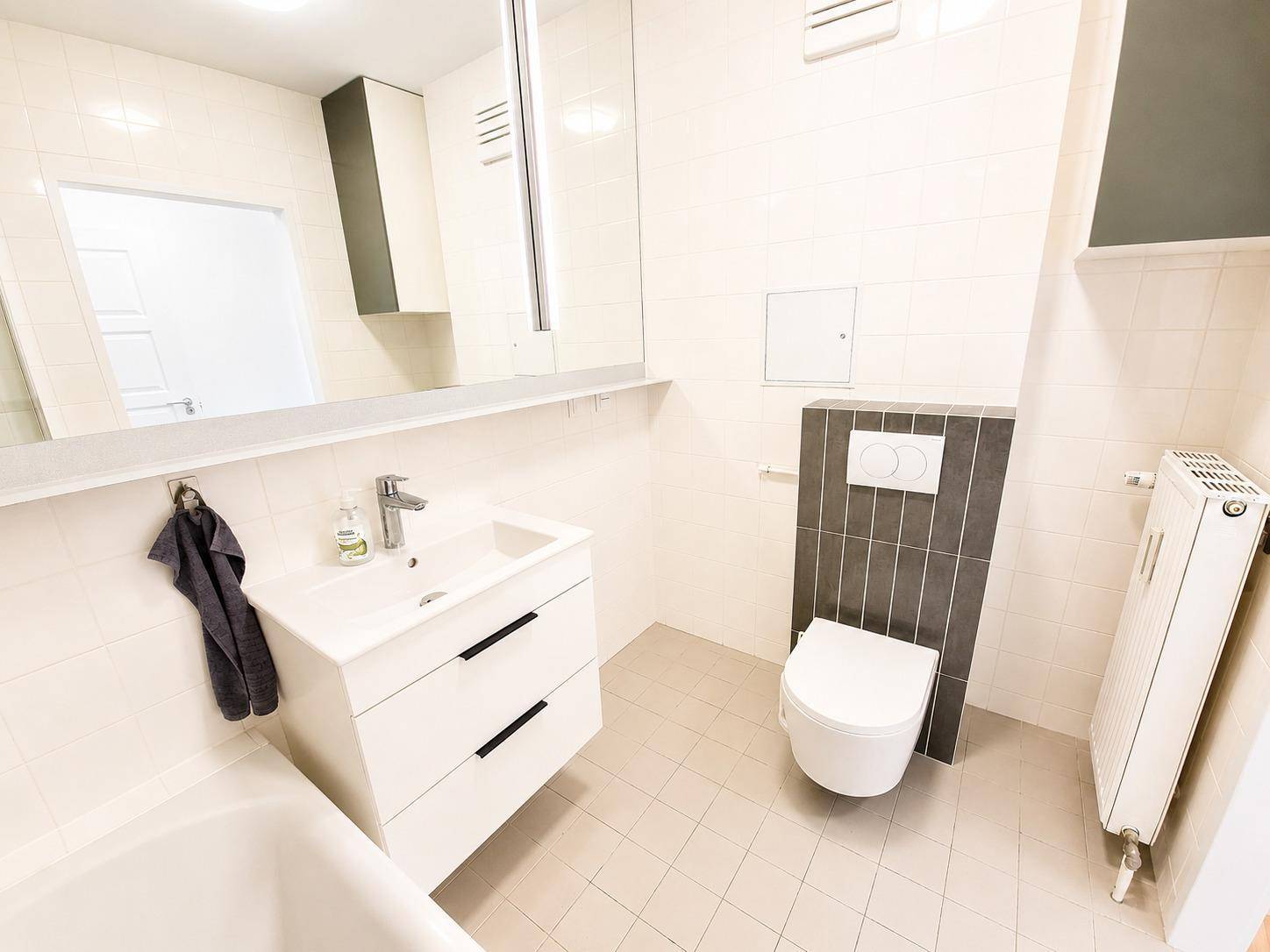 Helles Badezimmer mit Waschtisch, WC und Heizkörper, funktional und modern gestaltet.