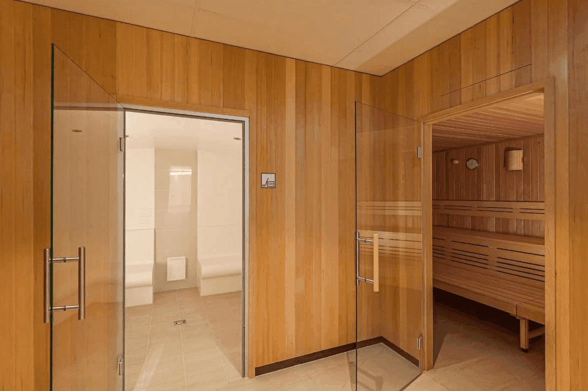 Eingangsbereich zu Sauna und Dampfbad mit Holzwänden und Glastüren.