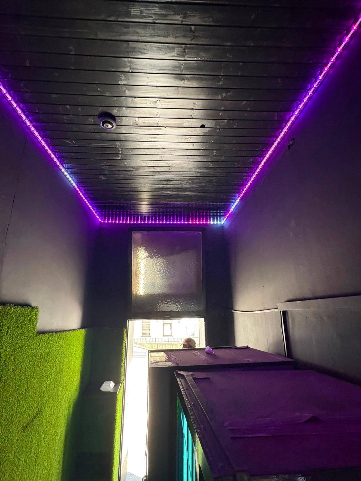 Decke eines Snack-Shops mit Holzverkleidung und farbigen LED-Lichtstreifen.