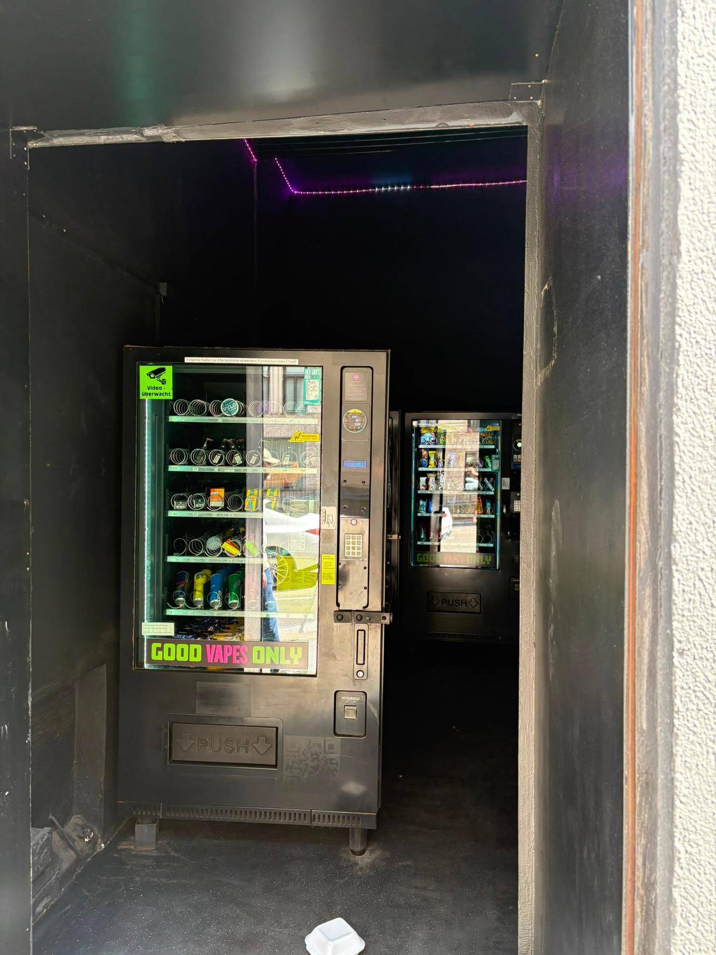 Innenansicht eines Snack-Shops mit mehreren Verkaufsautomaten und dunkler Einrichtung.