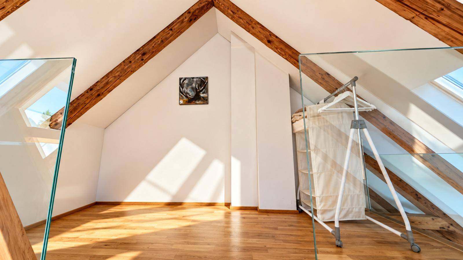 Heller offener Raum im Dachgeschoss mit Holzbalken, Dachfenstern und viel natürlichem Licht.