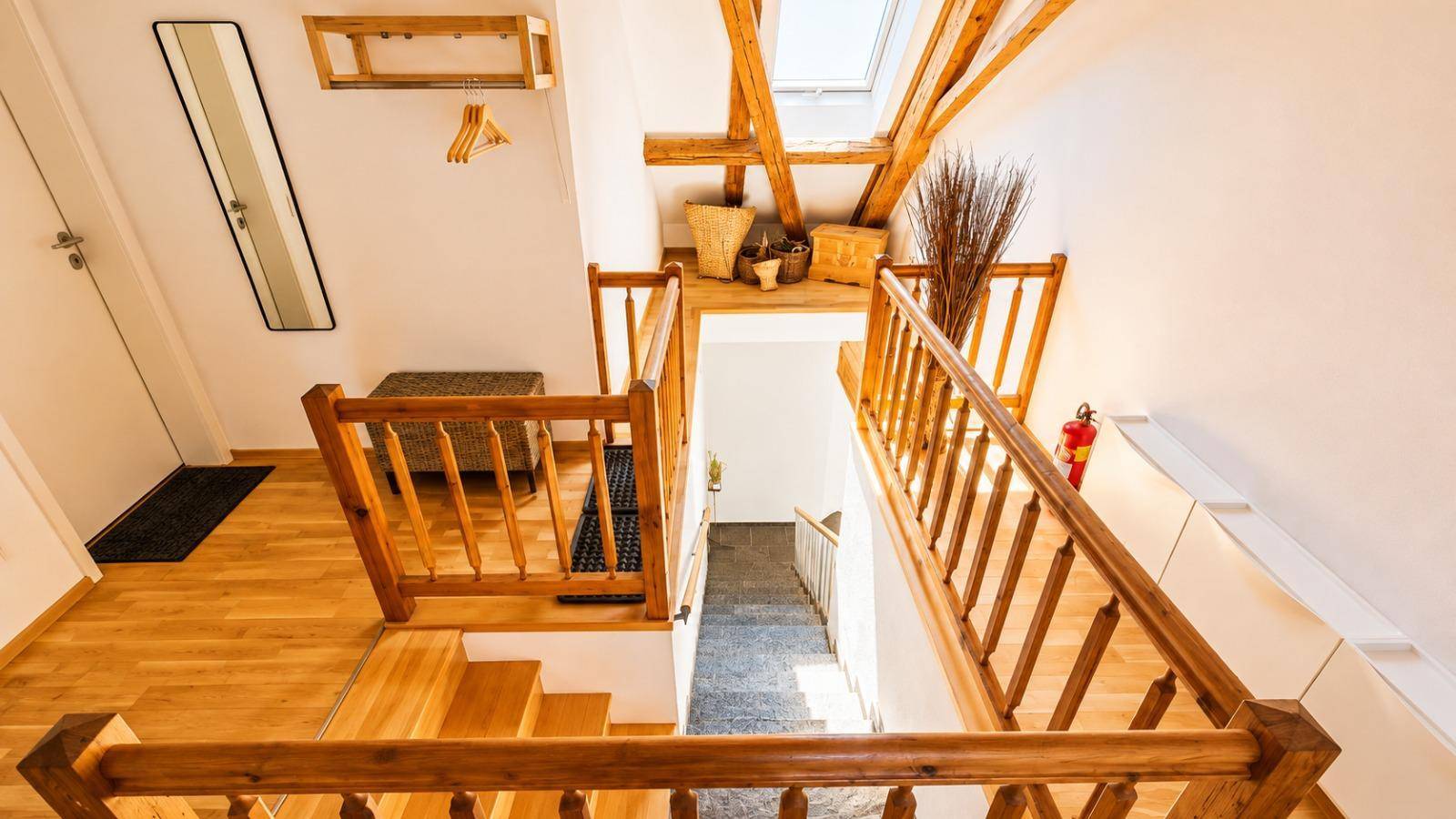 Holztreppe mit Geländer, die die verschiedenen Ebenen des Dachgeschosses miteinander verbindet.