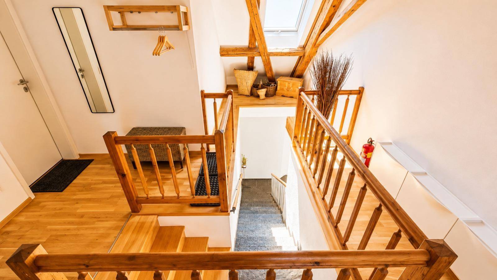 Blick von oben auf die Holztreppe mit Geländer, die verschiedene Ebenen des Hauses verbindet.