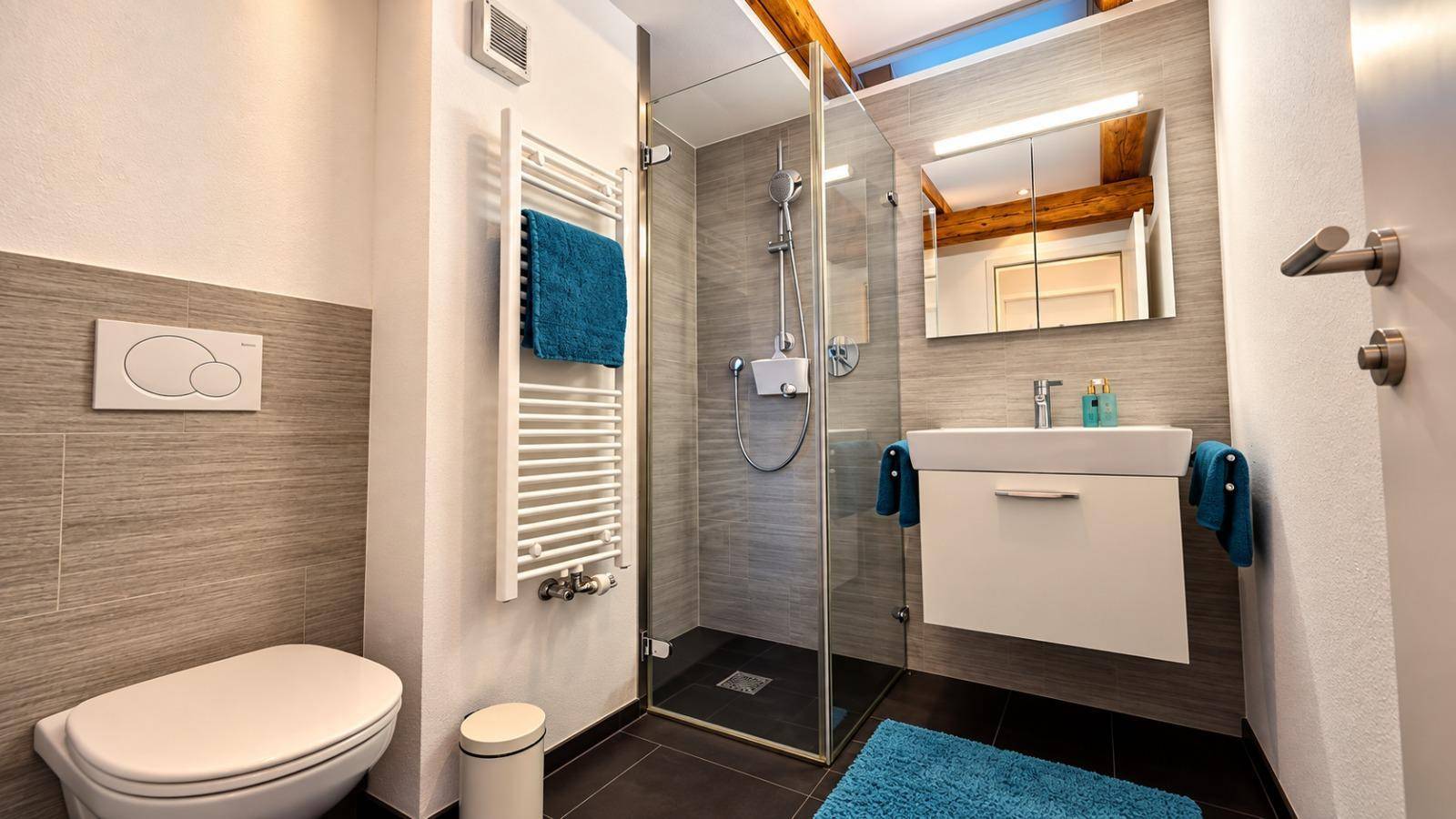 Modernes Badezimmer mit Duschkabine, wandhängendem WC, Waschbecken und beheiztem Handtuchhalter.