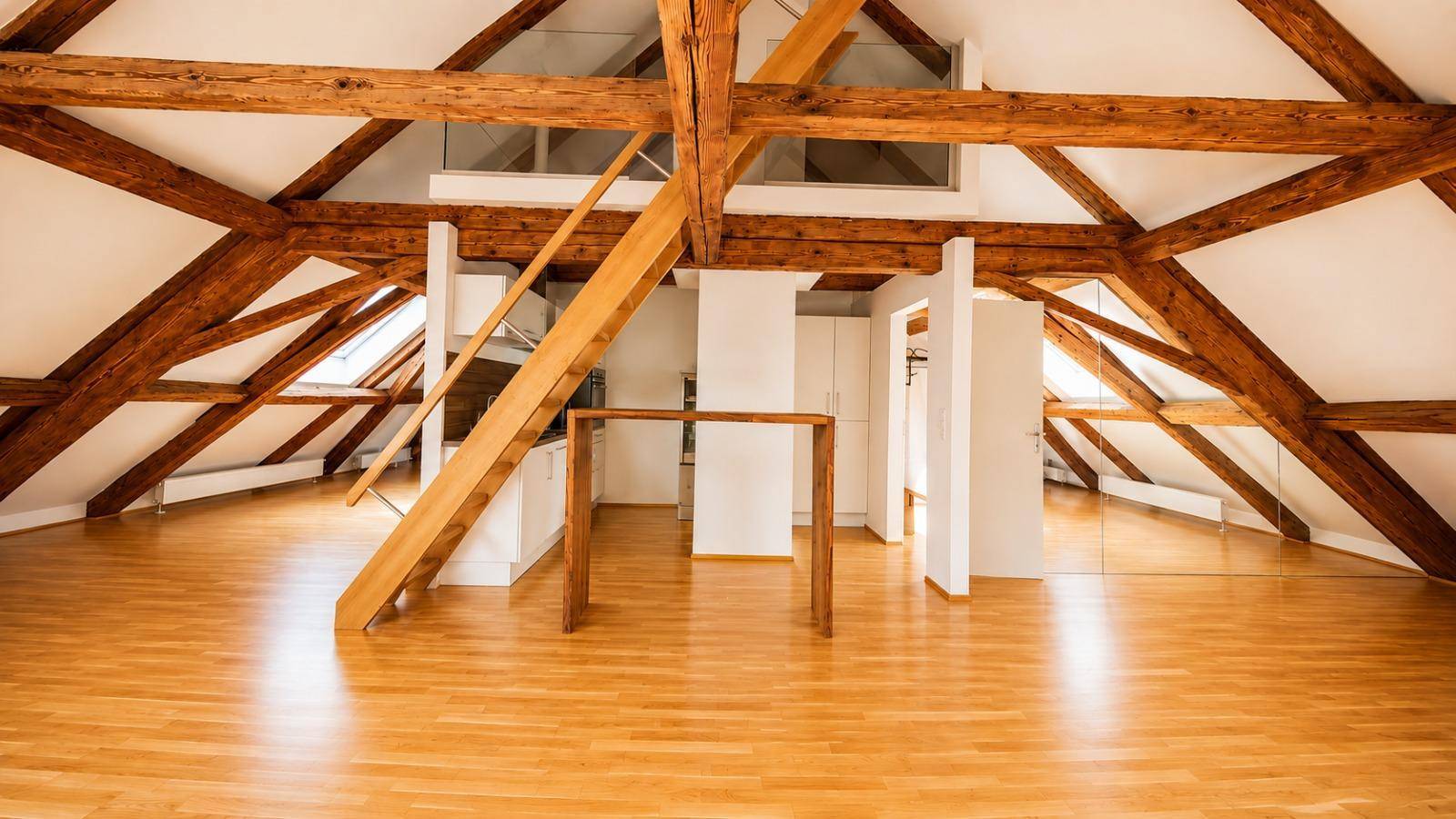 Offener Dachbodenbereich mit markanten Holzbalken, Holztreppe und hellem Parkettboden, der viel Raum bietet.
