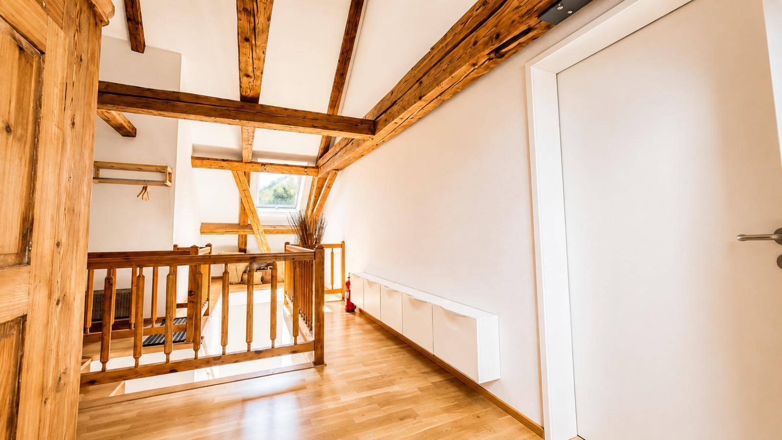 Treppenbereich mit Holzgeländer und einer modernen weißen Schrankwand, die Stauraum bietet.