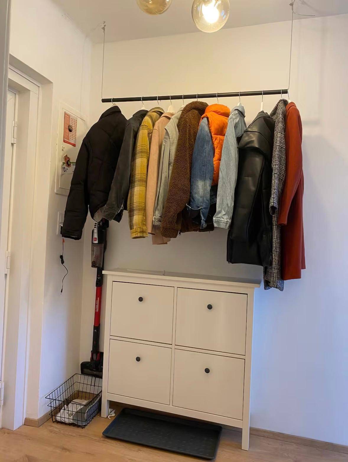 Eingangsbereich mit Garderobenstange, Schuhschrank und Holzboden.