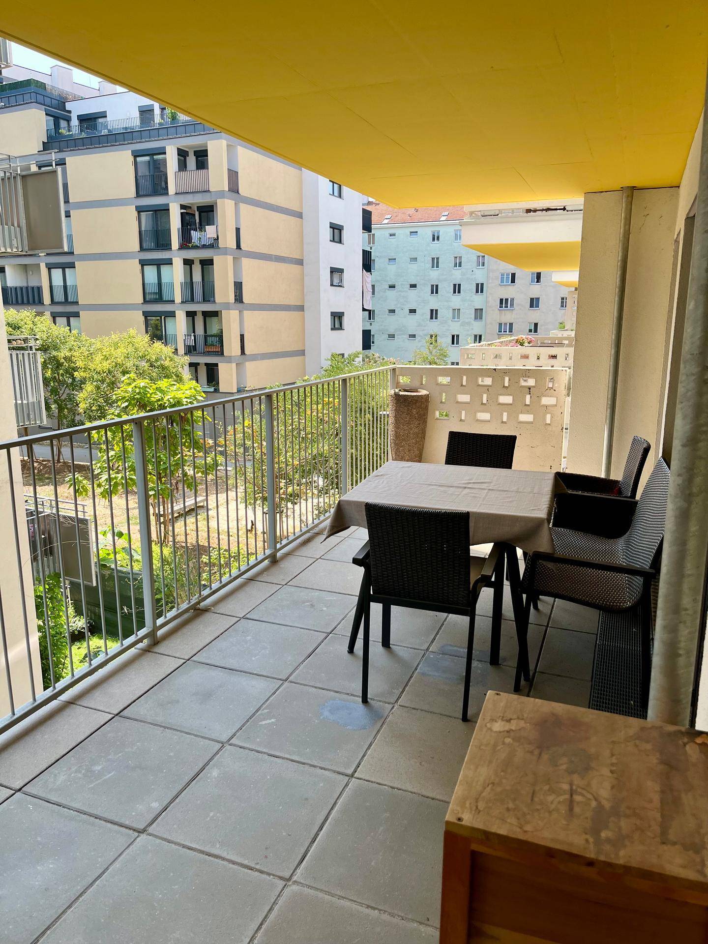 Möblierter Balkon mit Fliesenboden und Blick auf die umliegenden Wohngebäude.
