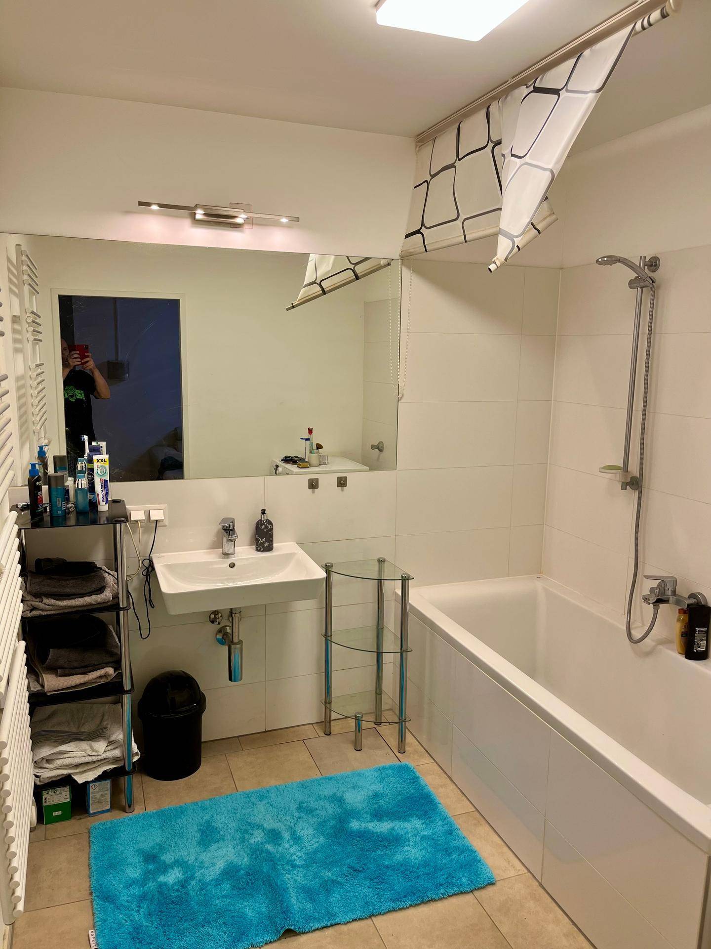 Modernes Badezimmer mit Badewanne, Dusche, Einzelwaschbecken und beheiztem Handtuchhalter.