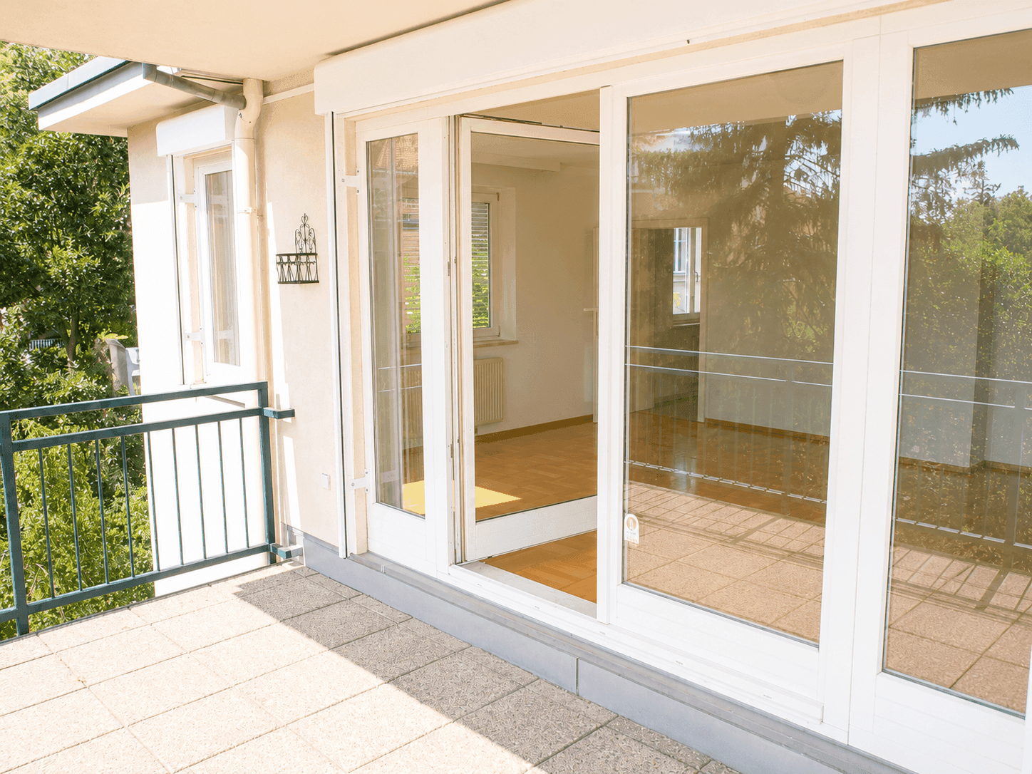 Geräumiger Balkon mit Fliesenboden und großen Fenstertüren, die in den Innenraum führen.