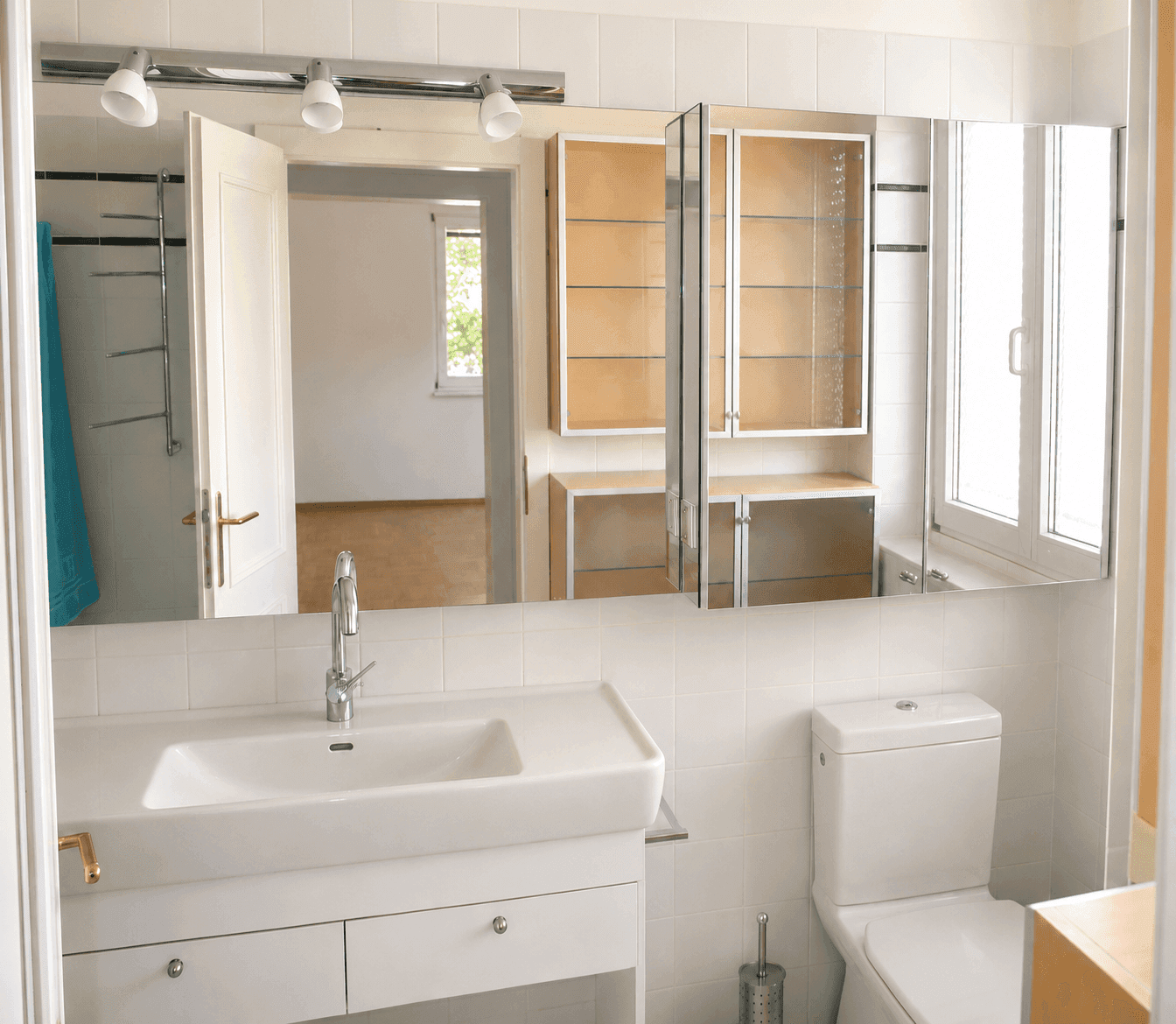 Modernes Badezimmer mit Waschbecken, Toilette und großem Spiegelschrank über dem Waschtisch.
