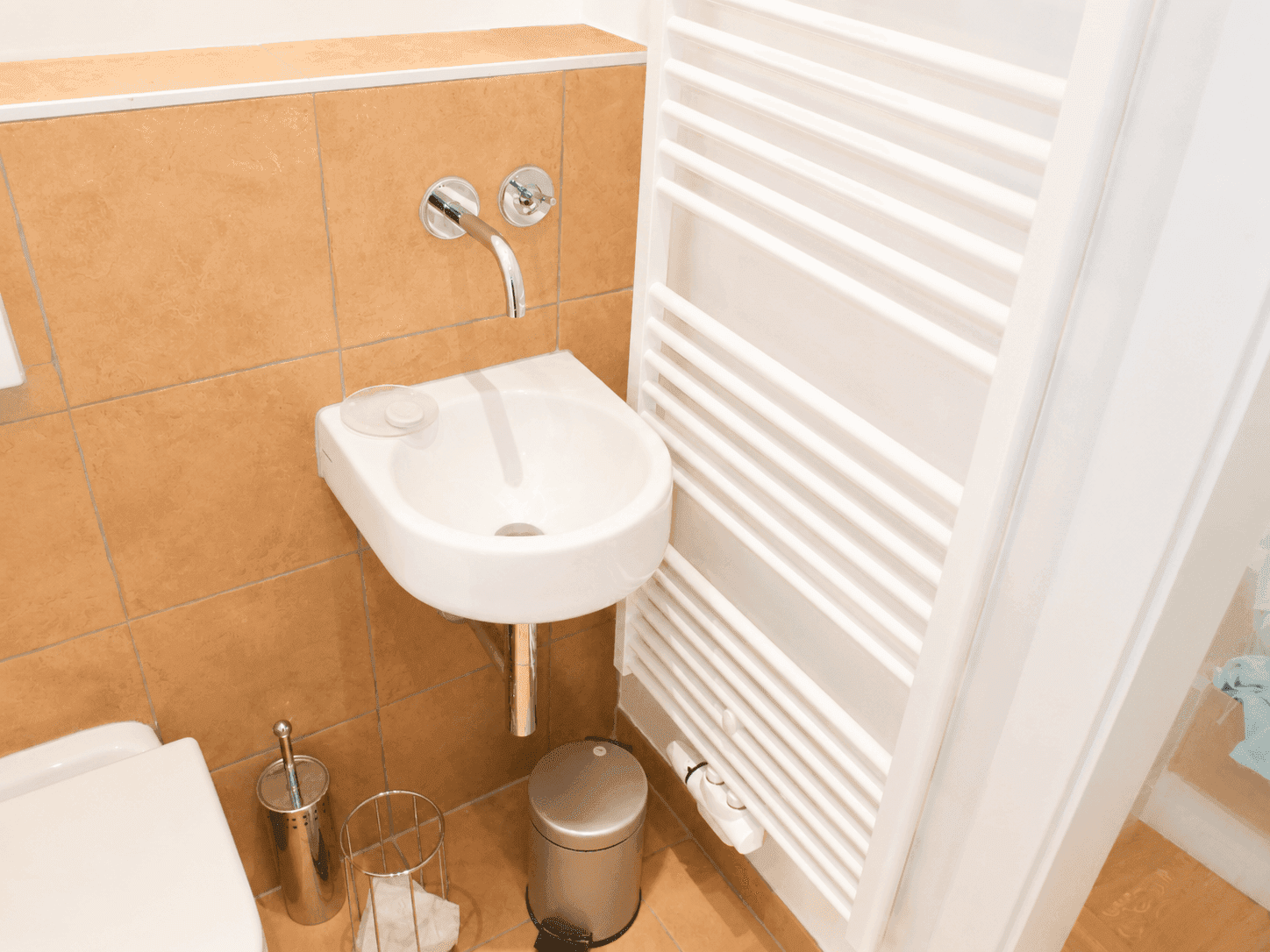 Kleines Gäste-WC mit Handwaschbecken, Wand-WC und beheiztem Handtuchhalter.
