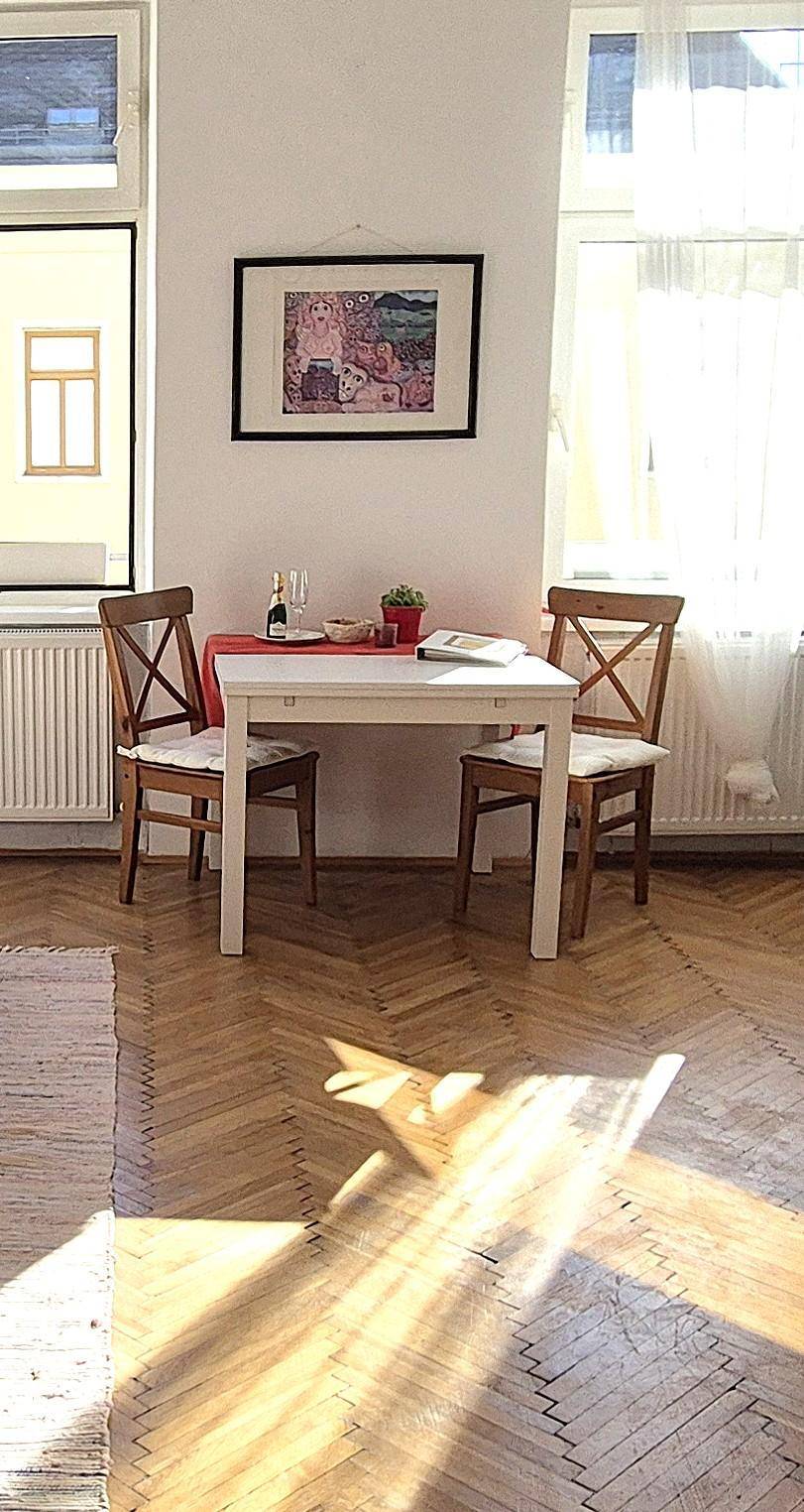 Gemütlicher Essbereich mit kleinem Tisch und Stühlen, beleuchtet durch natürliches Licht vom Fenster.