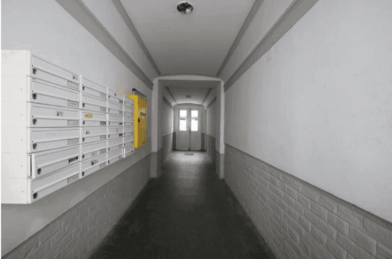 Langer Flur im Gebäude mit Reihen von Briefkästen und einem hellen Ende.