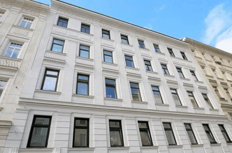 Klassische Fassade eines Mehrfamilienhauses mit vielen Fenstern und traditionellen Verzierungen.