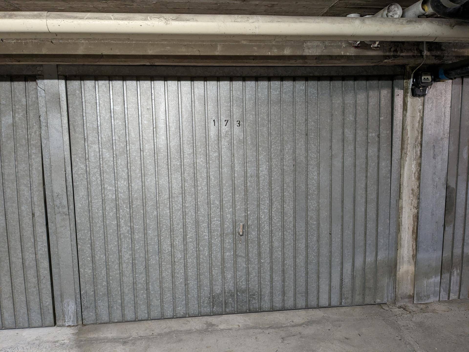 Geschlossenes Garagentor Nummer 173 in einer Tiefgarage mit Betonwänden und Decke.