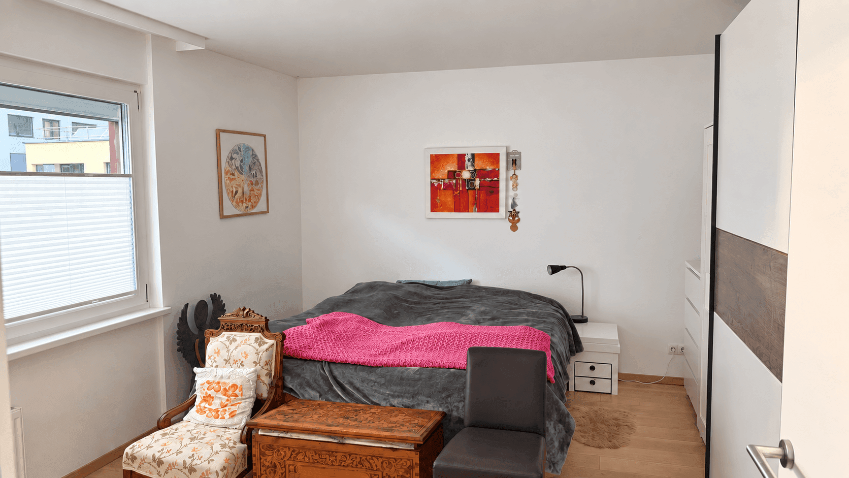Gemütliches Schlafzimmer mit Holzboden, großem Bett und Fenster mit Blick ins Grüne.