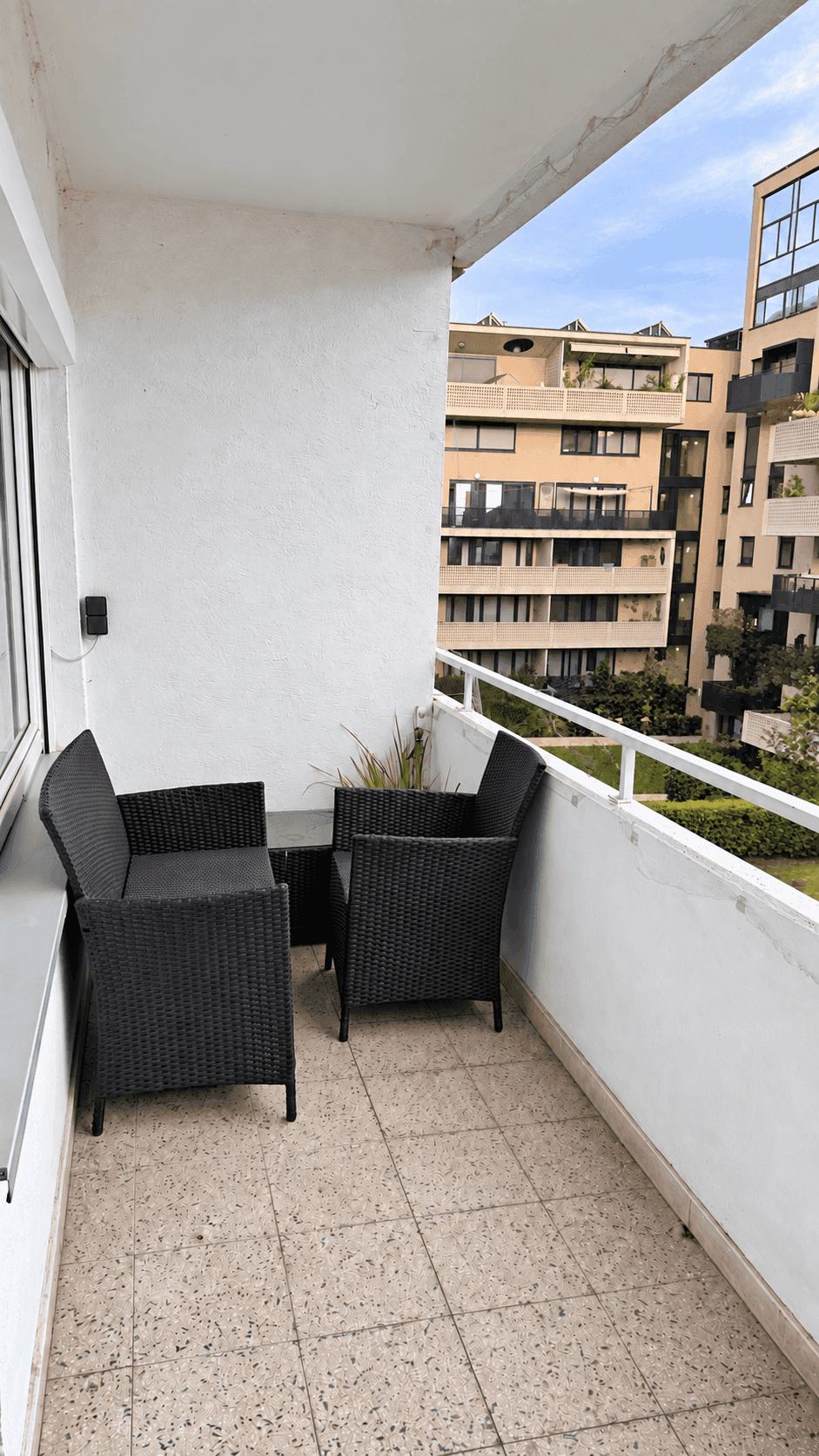 Kleiner Balkon mit Sitzgelegenheiten und Blick auf die umliegenden Gebäude.