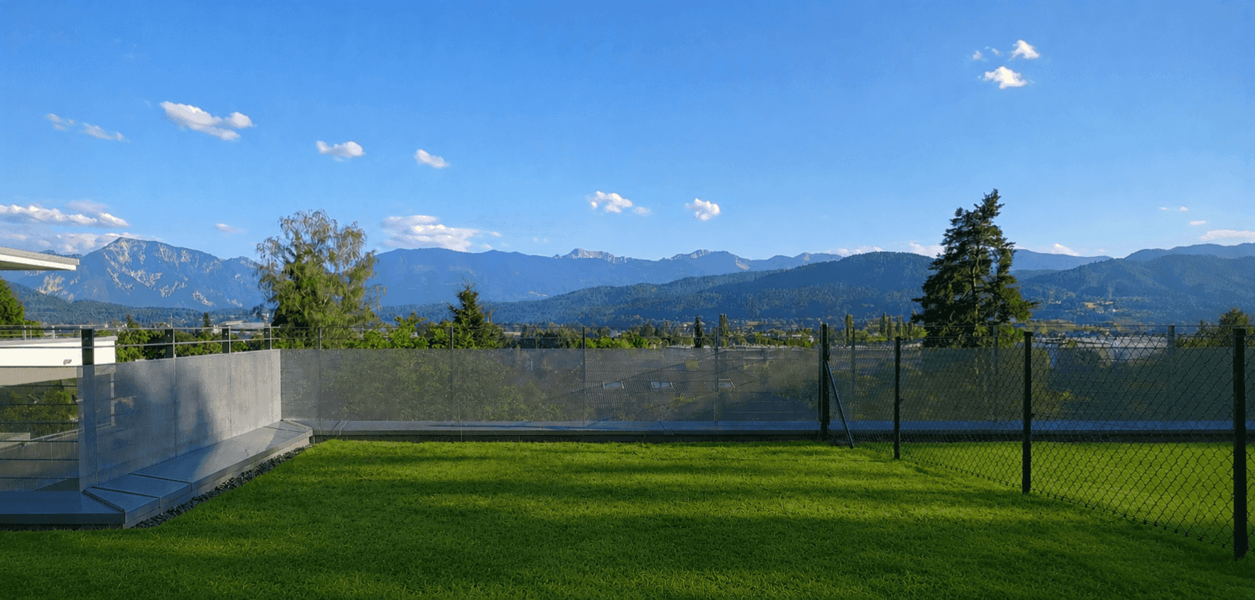 Gepflegter Gartenbereich mit weitem Blick auf die umliegende Berglandschaft und das Tal.