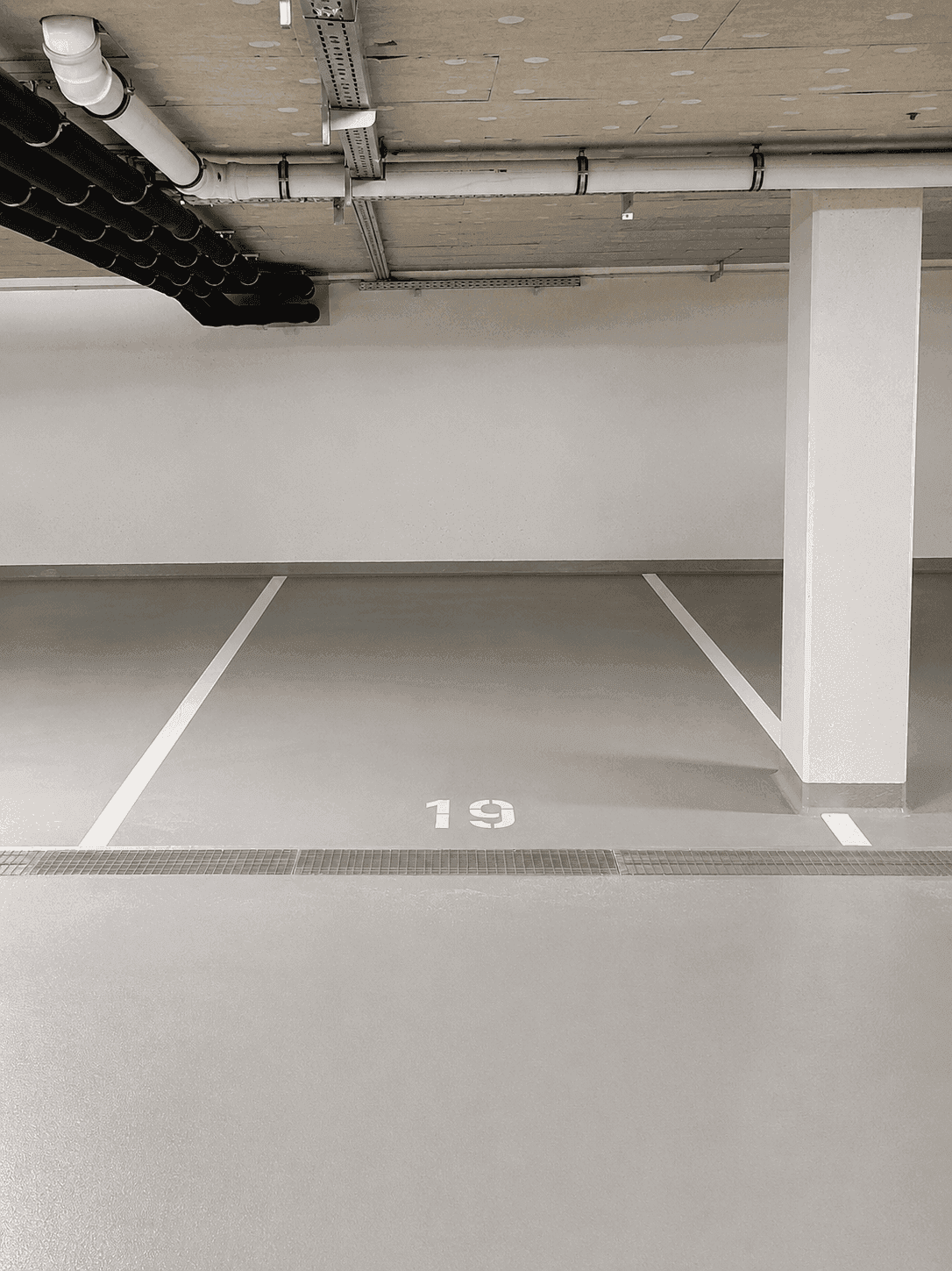 Tiefgaragenstellplatz Nummer 19 mit sichtbaren Leitungen an der Decke.