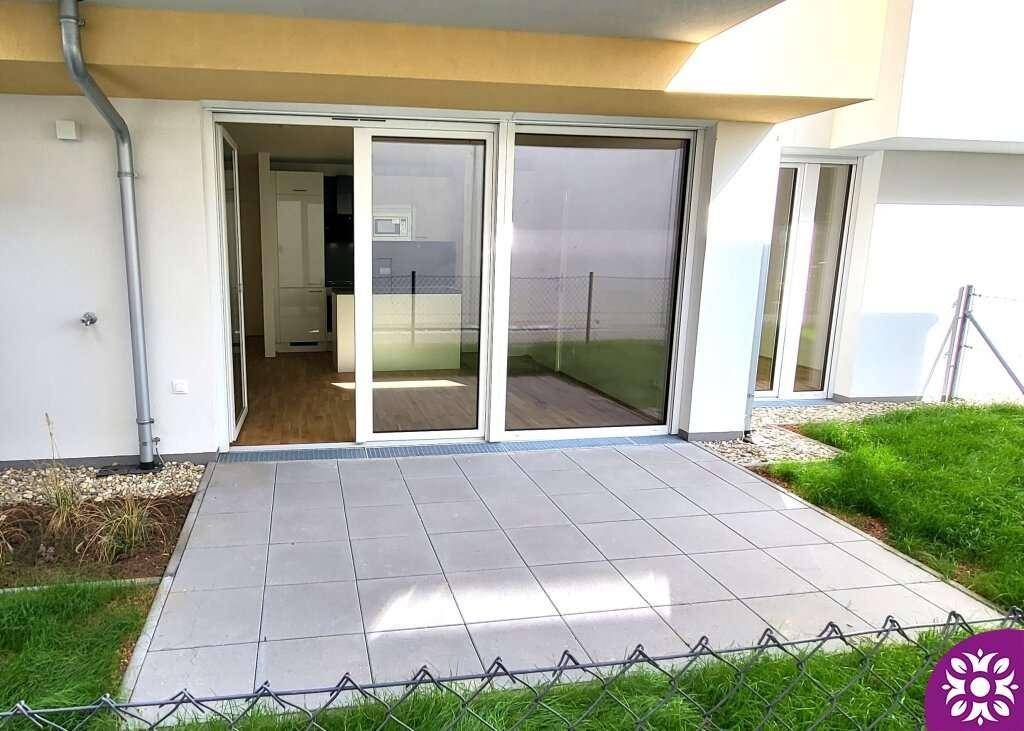 Außenterrasse mit Fliesenboden und Blick auf den Garten, direkt zugänglich vom Wohnbereich.