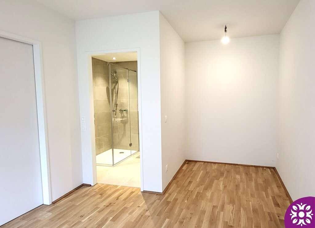 Schlafzimmer mit Holzboden und direktem Zugang zu einem modernen Duschbad.