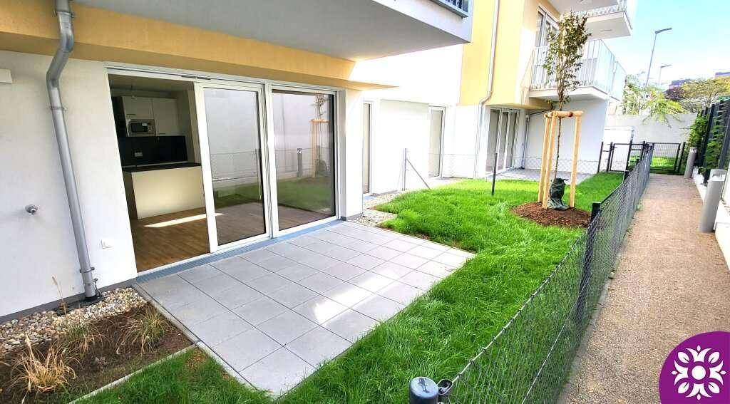 Gepflegter Gartenbereich mit Terrasse und junger Bepflanzung neben einem modernen Gebäude.