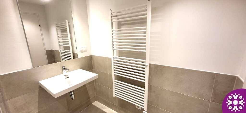 Modernes Badezimmer mit Waschbecken, Spiegel und beheiztem Handtuchhalter.