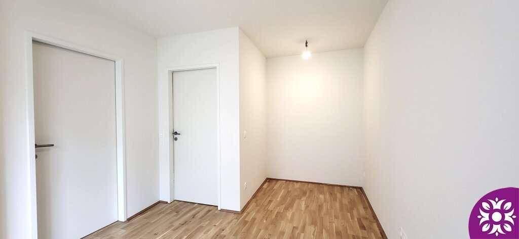 Kleiner, heller Raum mit Holzboden und zwei weißen Türen.