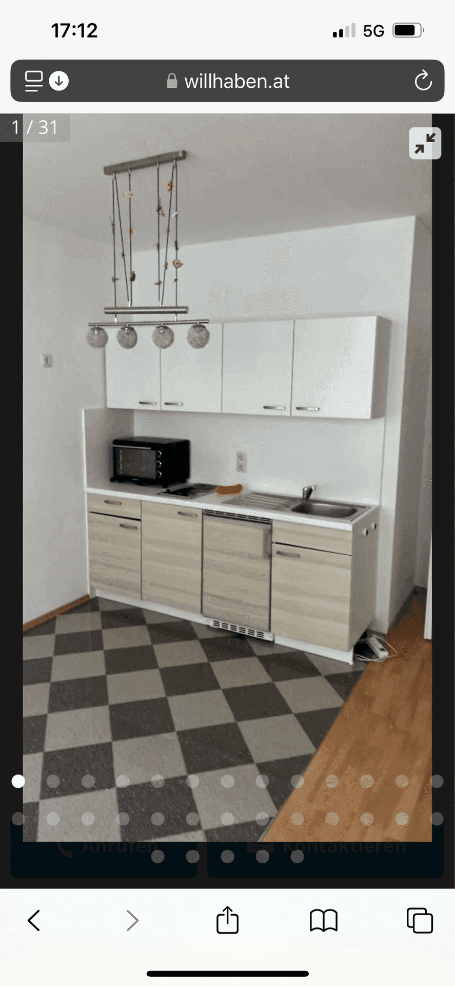 Kompakte Küchenzeile mit kariertem Fliesenboden und modernen Schränken in einem Studio.