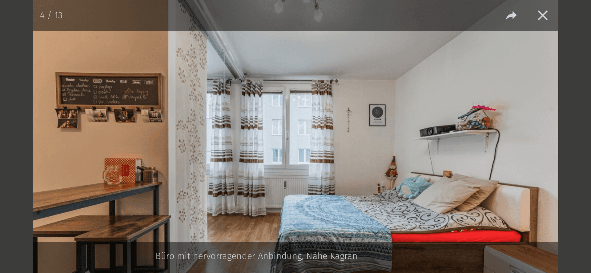 Gemütliches Schlafzimmer mit Bett, Holzboden und Fenster mit Vorhängen.