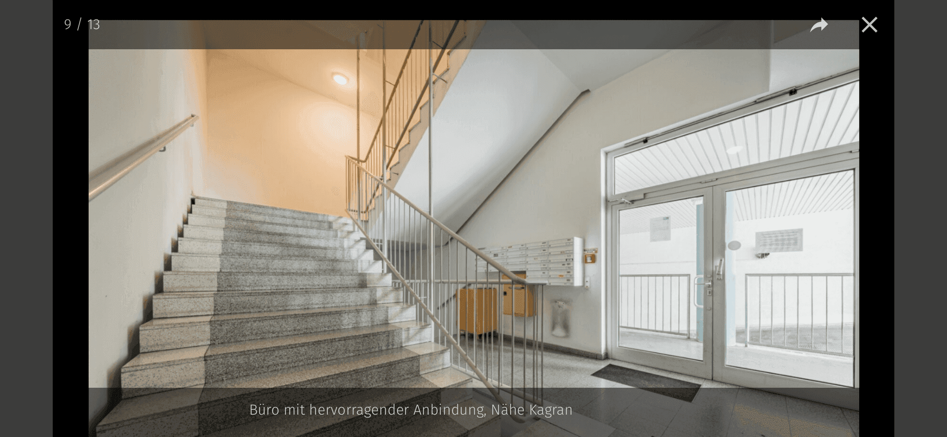 Treppenhaus mit Granitstufen und Metallgeländer, führt zu den oberen Etagen.