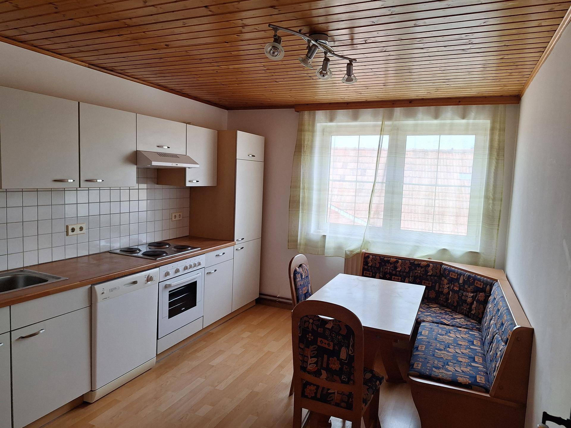 Helle Wohnküche mit Einbauküche, Essbereich und Holzdecke.