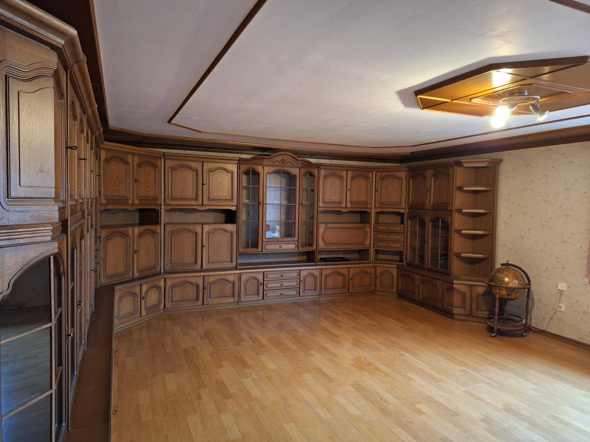 Geräumiges Wohnzimmer mit traditioneller Holzvertäfelung, Einbauschränken und Parkettboden.