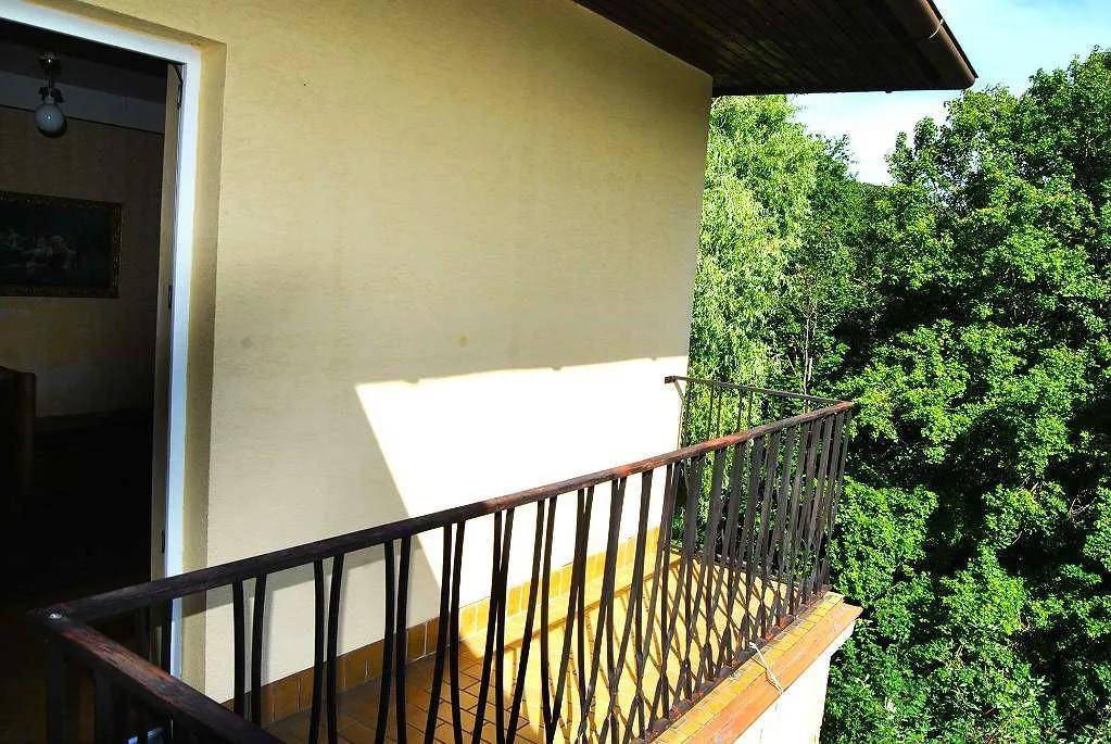 Kleiner Balkon mit schmiedeeisernem Geländer und Blick ins Grüne.