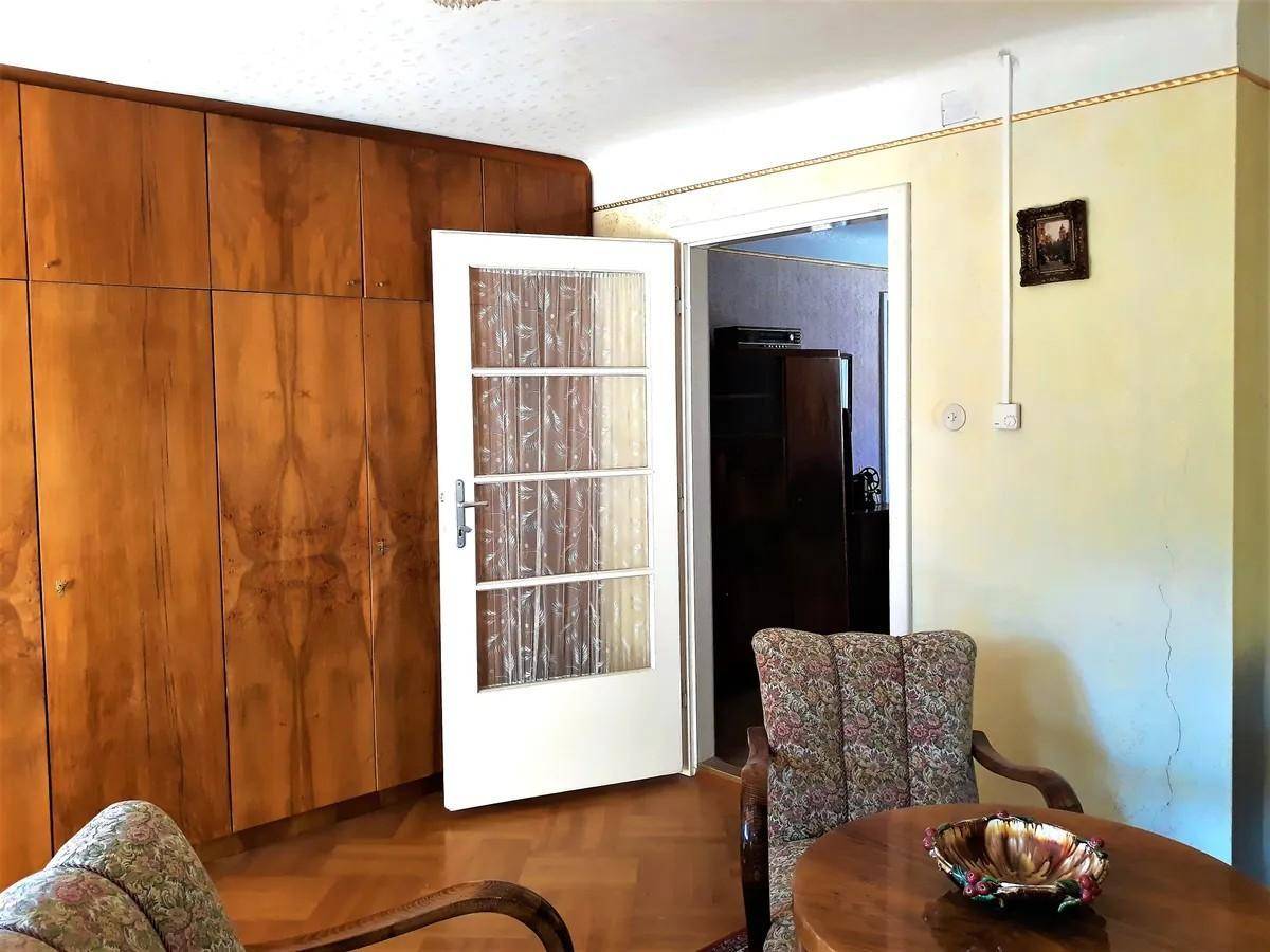 Wohnzimmer mit großen Holzschränken und einer Tür zu einem weiteren Raum.