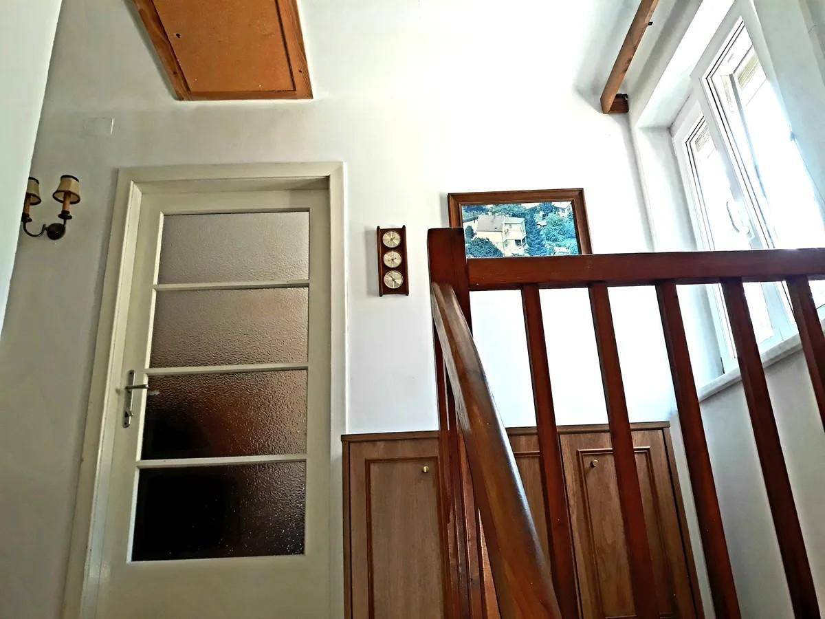 Treppenhaus mit Holzgeländer und einer Tür, die zu einem weiteren Bereich führt.