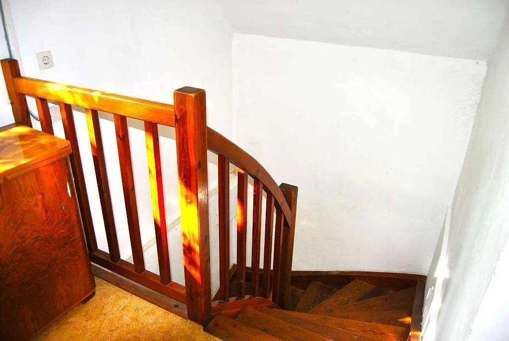 Holztreppe mit Geländer, die in ein unteres Stockwerk führt.