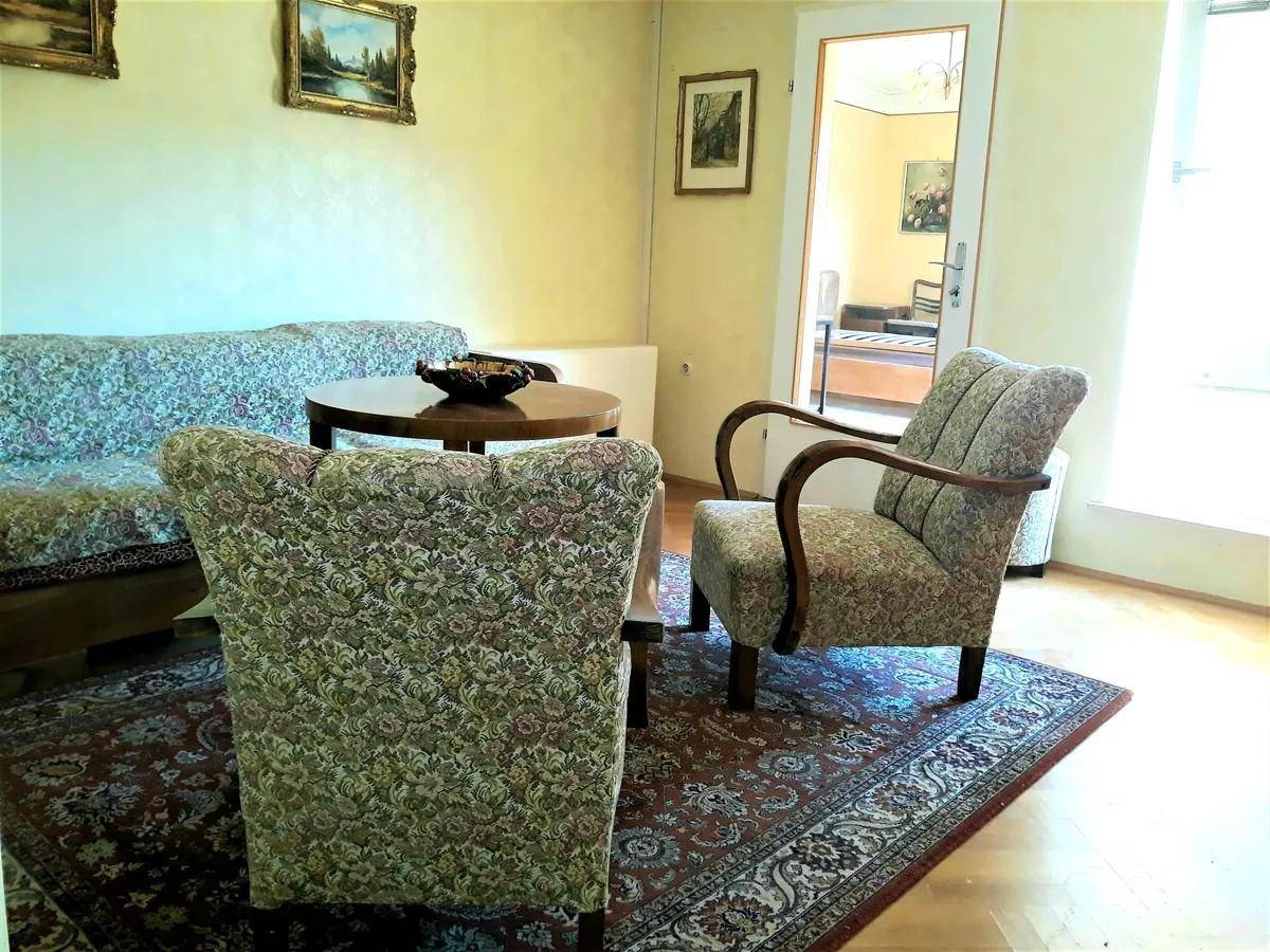 Wohnzimmer mit bequemen Sesseln, Sofa und einem runden Holztisch.
