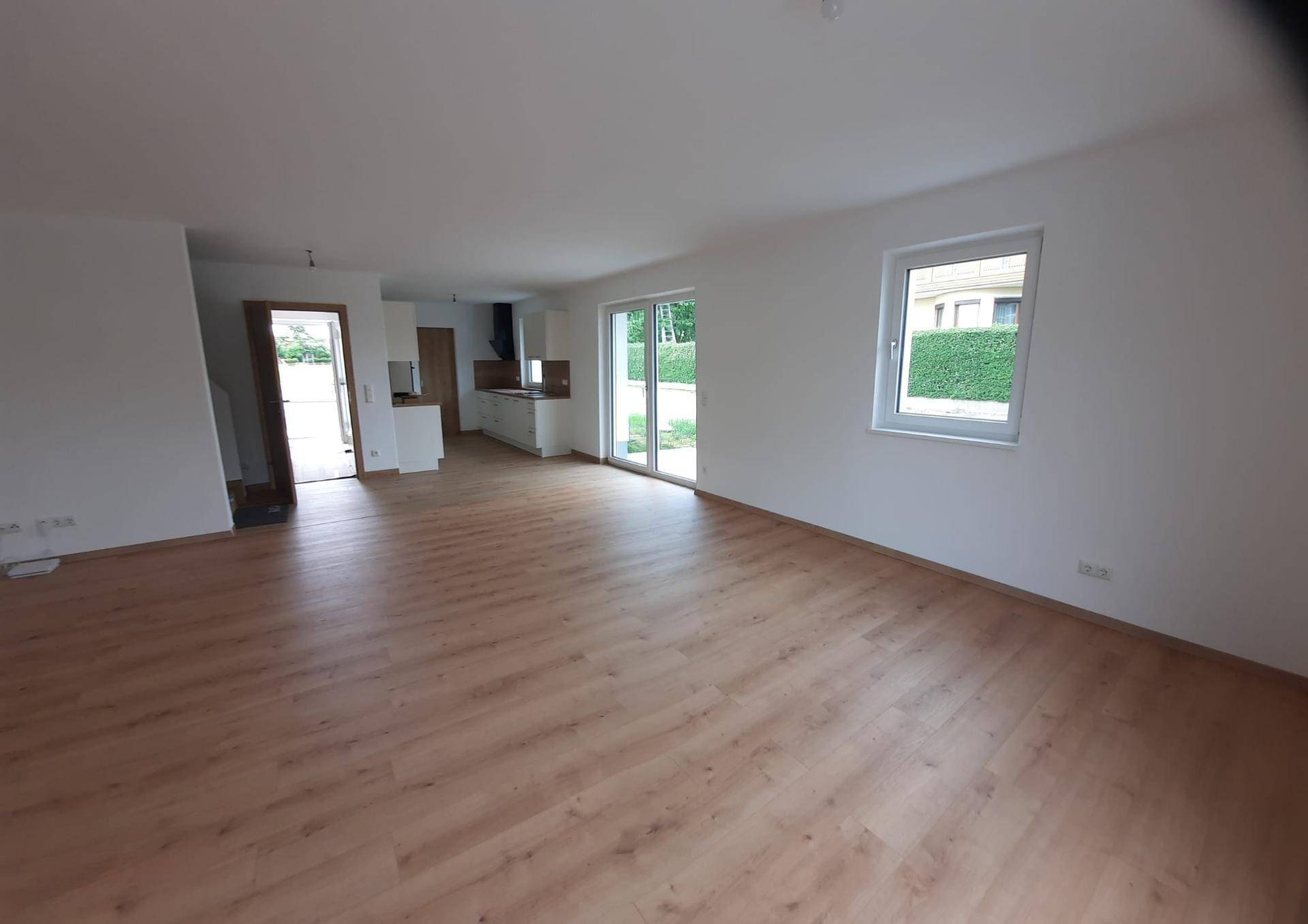 Geräumiger, offener Wohn- und Essbereich mit Laminatboden und Blick auf die angrenzende Küche.
