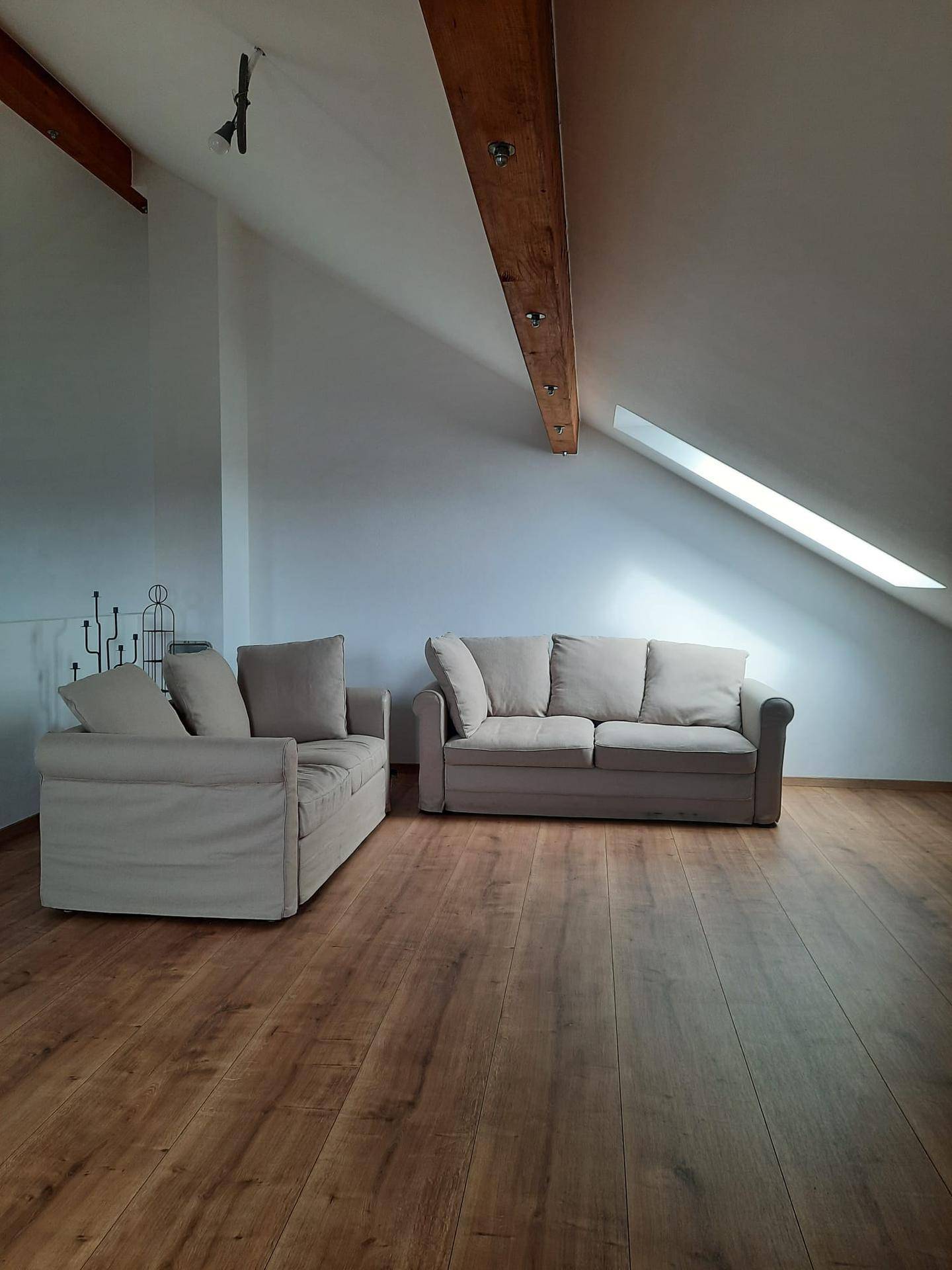 Gemütliche Sitzecke im Dachgeschoss mit bequemen Sofas und schrägen Wänden.