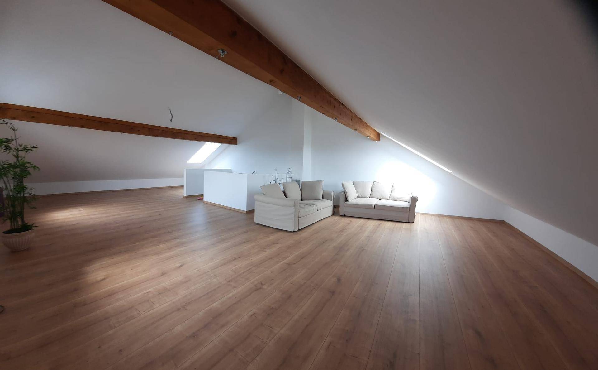 Weitläufiger Dachbodenraum mit gemütlichen Sofas, Holzbalken und viel natürlichem Licht.